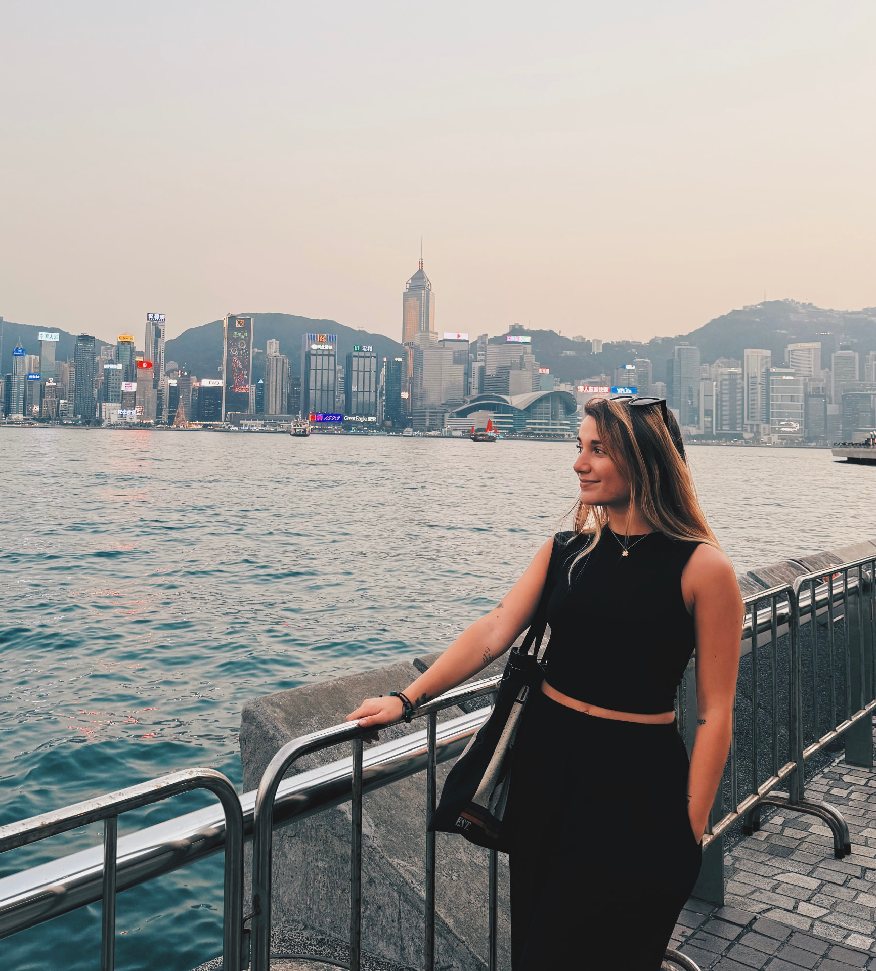 Ilaria Lico on the waterfront at sunset with a city skyline behind her